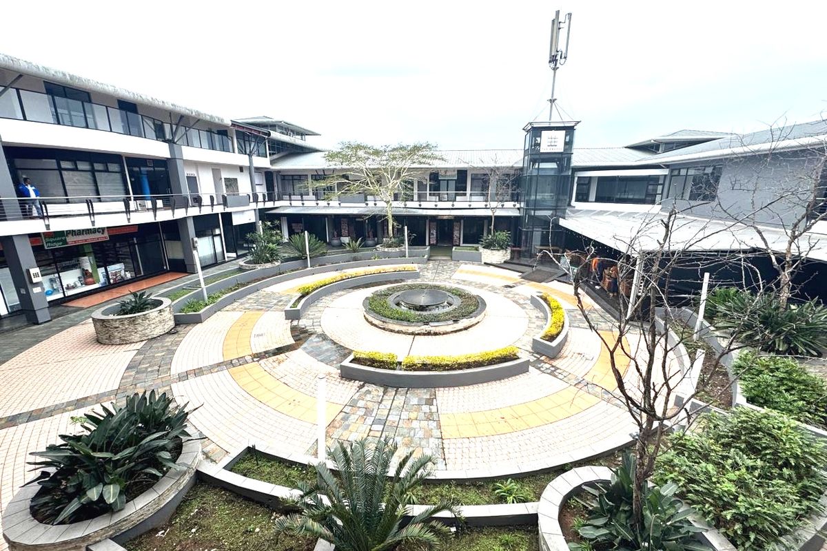 A central courtyard featuring a circular paved design, a water fountain, and landscaped planters surrounded by a multi-level office building complex.