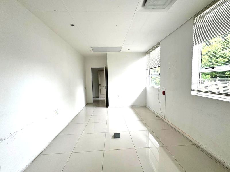 An empty office space featuring tiled flooring, suspended ceilings, and large windows with venetian blinds, ready for professional fit-out.