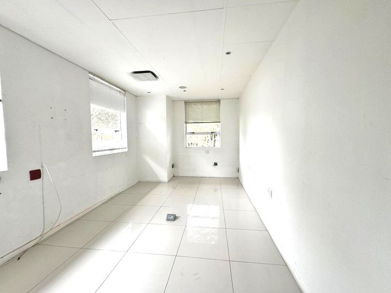A vacant, well-lit office space featuring tiled flooring, recessed ceiling lighting, and dual windows with fitted blinds, ready for custom configuration.