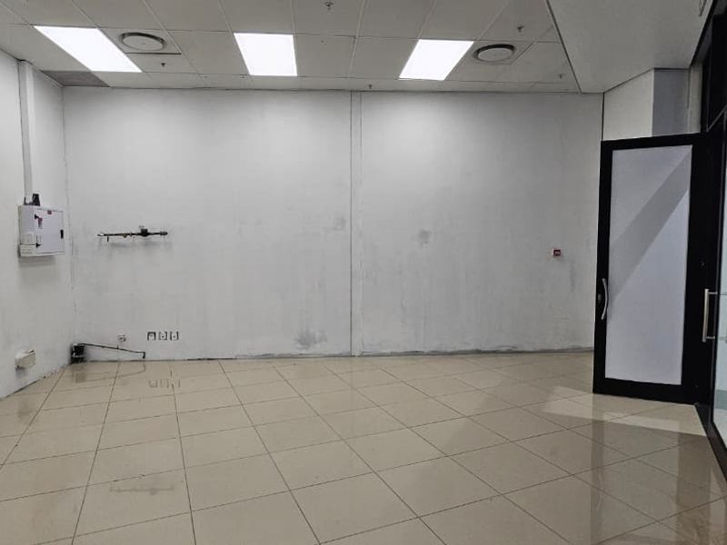 An empty retail or office space featuring tiled flooring, a suspended ceiling with recessed lighting, and a glass entrance door.