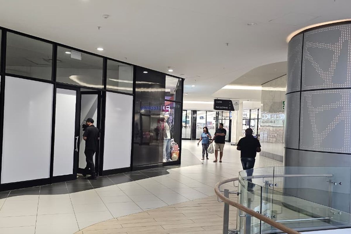 A modern retail storefront entrance within a shopping center, featuring glass paneling, tiled floors, and contemporary architectural finishes.