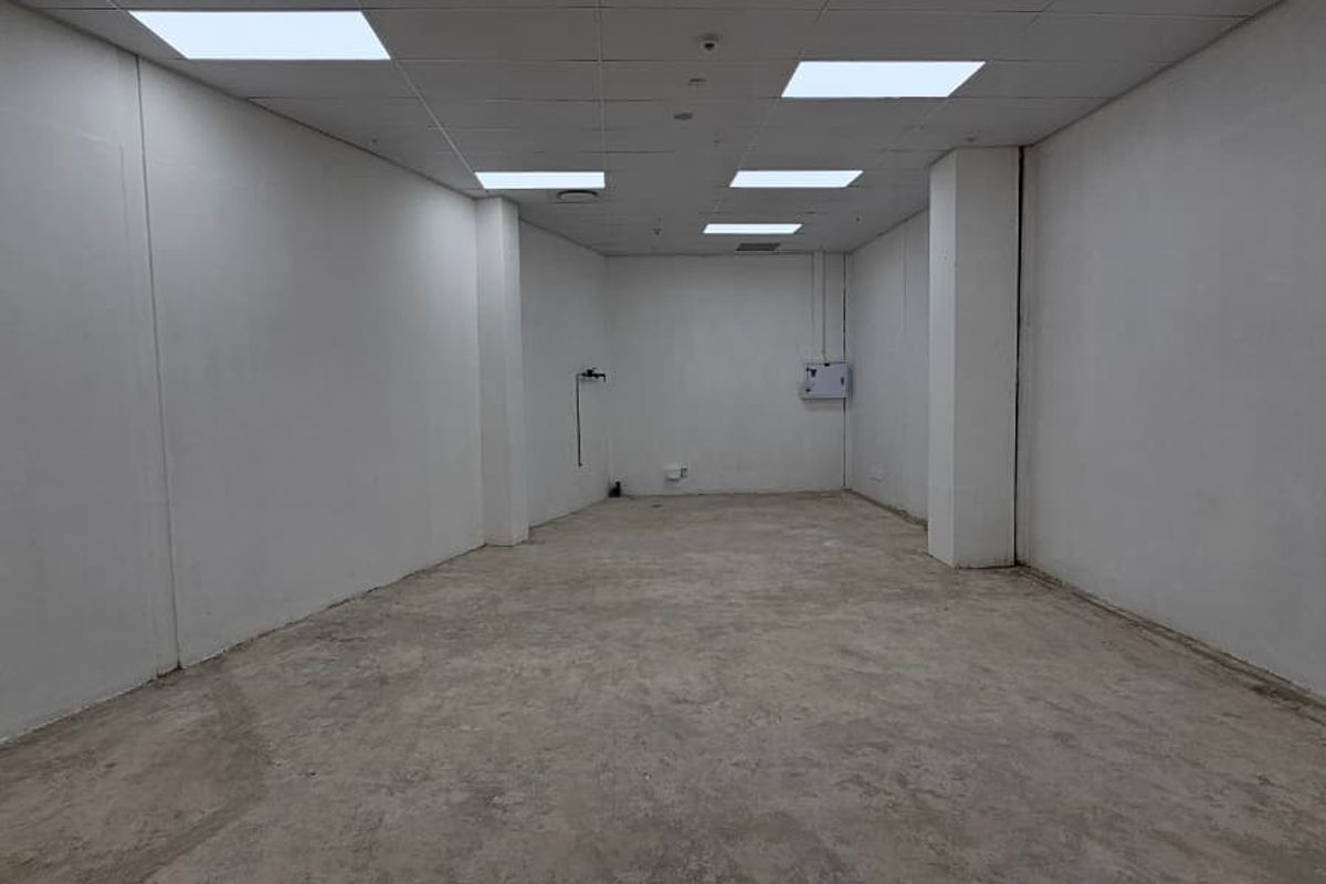 A vacant, open-plan retail space featuring a suspended ceiling with recessed lighting and unfinished concrete flooring, ready for custom fit-out.