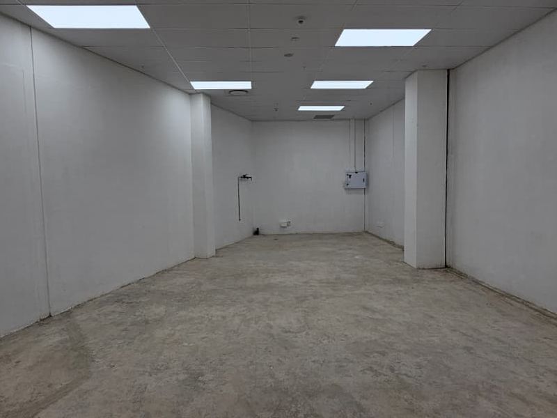 A vacant, open-plan retail space featuring a suspended ceiling with recessed lighting and unfinished concrete flooring, ready for custom fit-out.