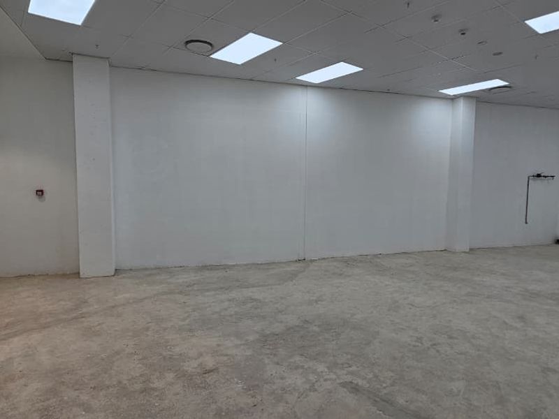 A vacant, open-plan retail space featuring a suspended ceiling, recessed lighting, and an unfinished concrete floor, ready for custom fit-out.