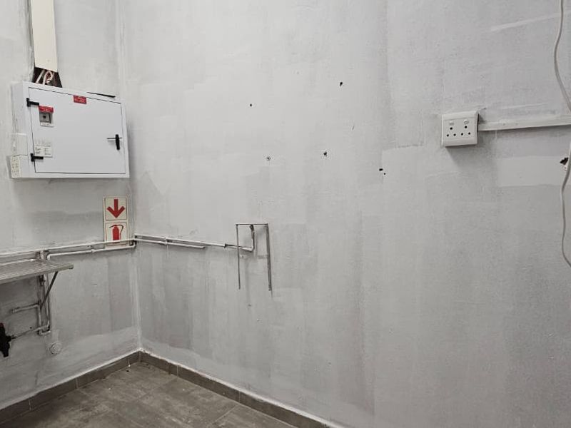 A functional utility space featuring a stainless steel sink, electrical distribution board, and tiled flooring, suitable for storage or service requirements.