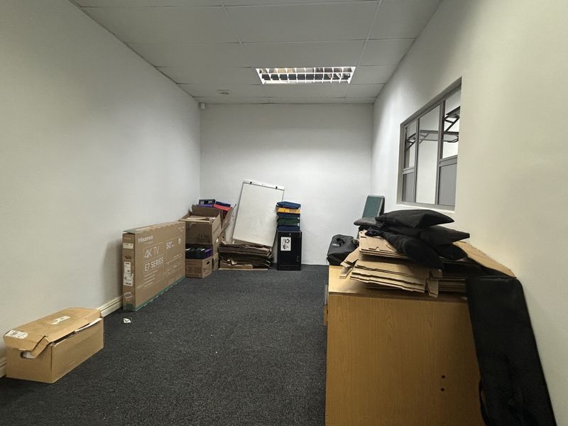 A functional office space featuring a suspended ceiling, recessed lighting, and carpeted flooring, suitable for a professional work environment.