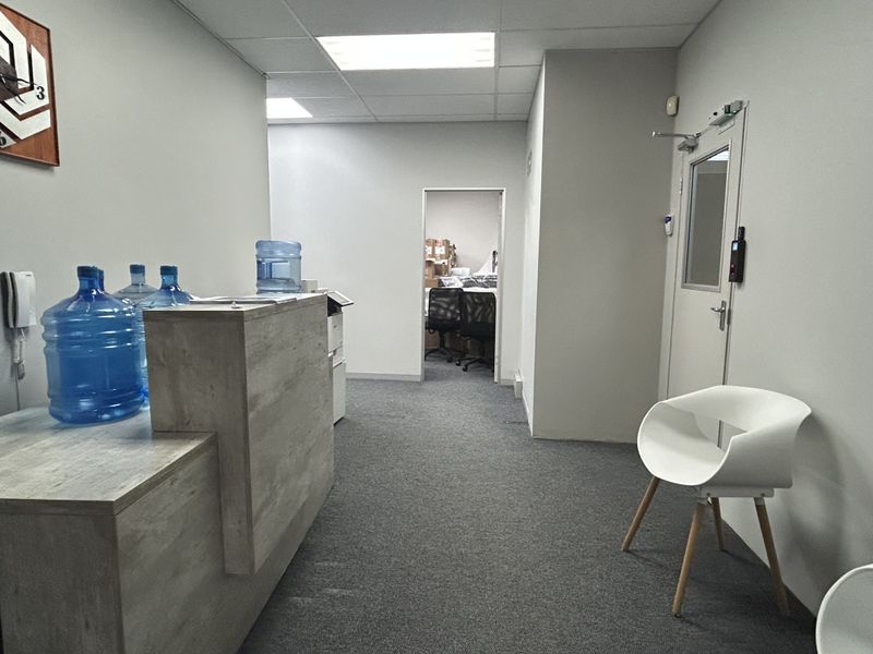 A commercial reception area featuring a built-in reception desk, carpeted flooring, and a secure access door leading to an inner office space.