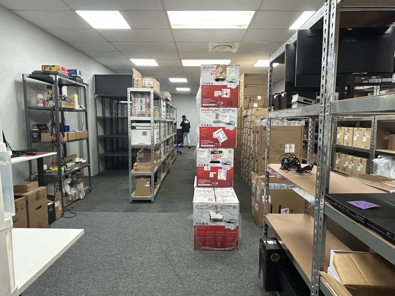 A functional commercial utility or storage space featuring industrial metal shelving, carpeted flooring, and a suspended ceiling with recessed lighting.