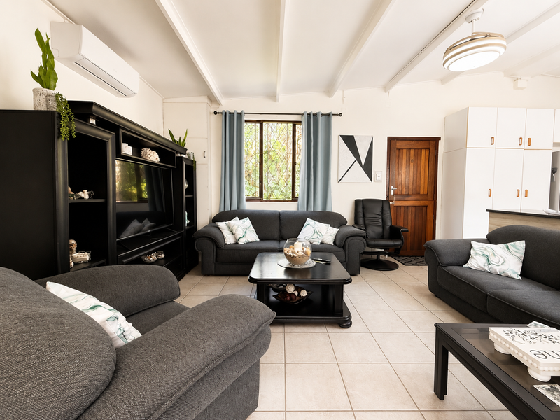 Spacious open-plan living area featuring tiled floors, exposed beam ceilings, and built-in cabinetry, offering a comfortable and functional layout.