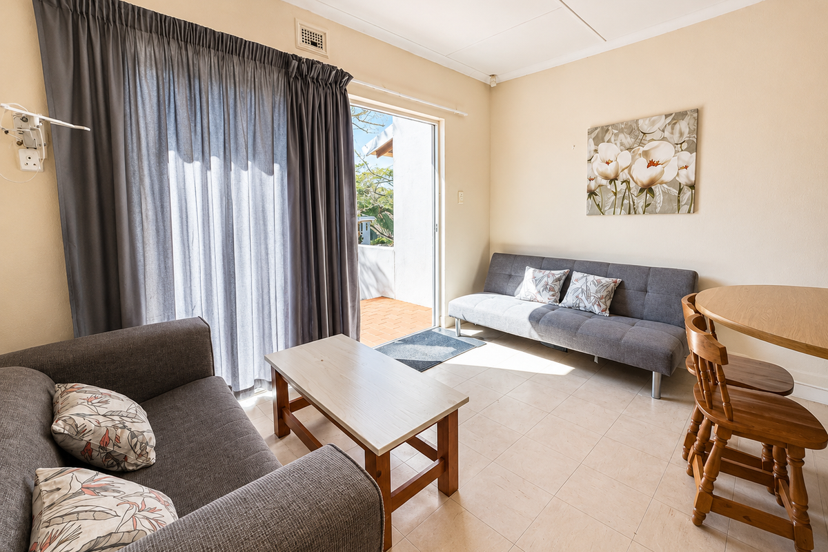 A bright living area featuring tiled flooring and a sliding glass door providing direct access to an outdoor patio space.