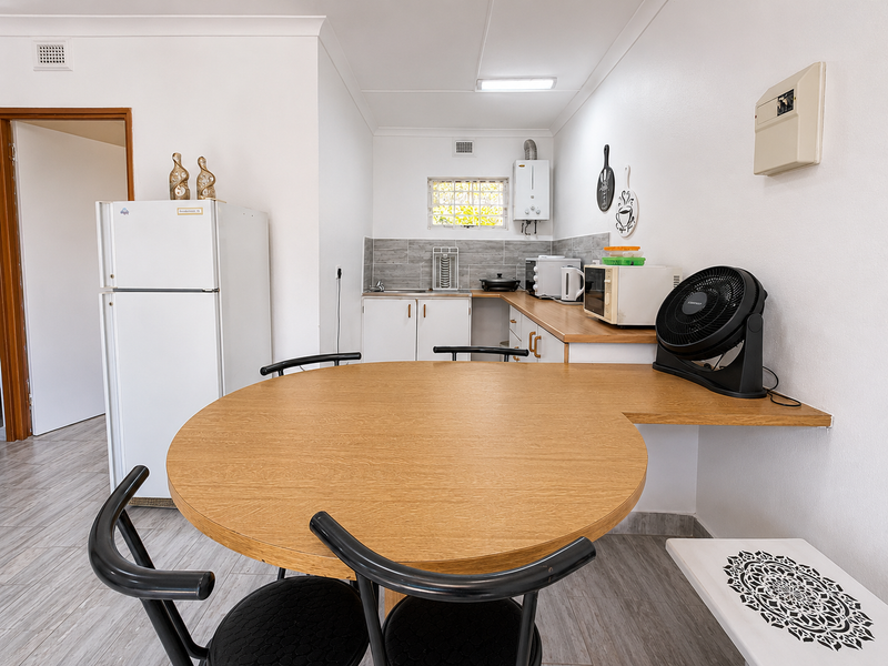 A functional kitchen area featuring built-in cabinetry, a tiled backsplash, and a gas water heater, integrated with a dining space.