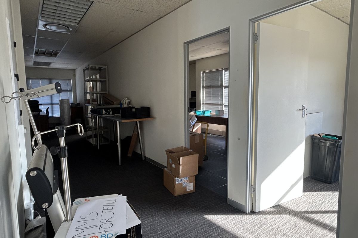 Office space featuring suspended ceilings, recessed lighting, and carpeted flooring, with an adjoining room accessible through an internal doorway.