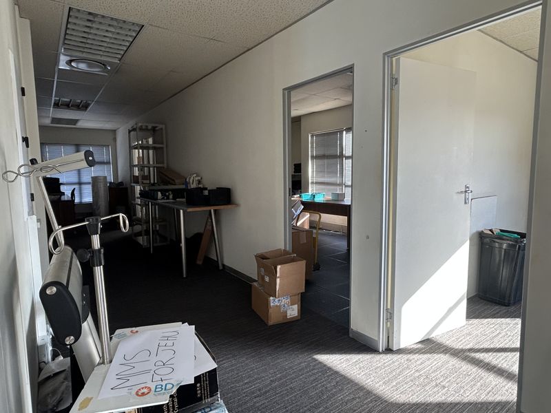 Office space featuring suspended ceilings, recessed lighting, and carpeted flooring, with an adjoining room accessible through an internal doorway.
