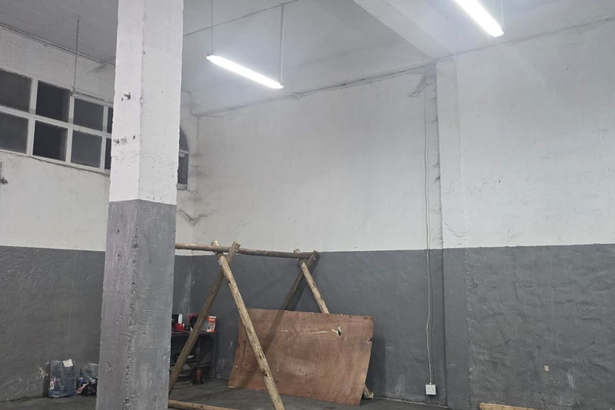 An industrial utility space featuring high ceilings, exposed concrete support columns, and clerestory windows, offering a versatile area for storage or workshop use.