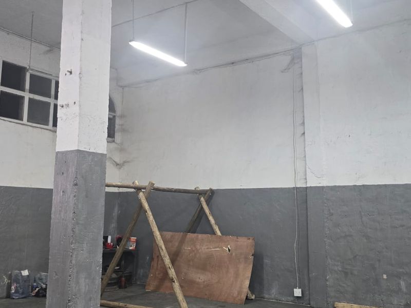 An industrial utility space featuring high ceilings, exposed concrete support columns, and clerestory windows, offering a versatile area for storage or workshop use.