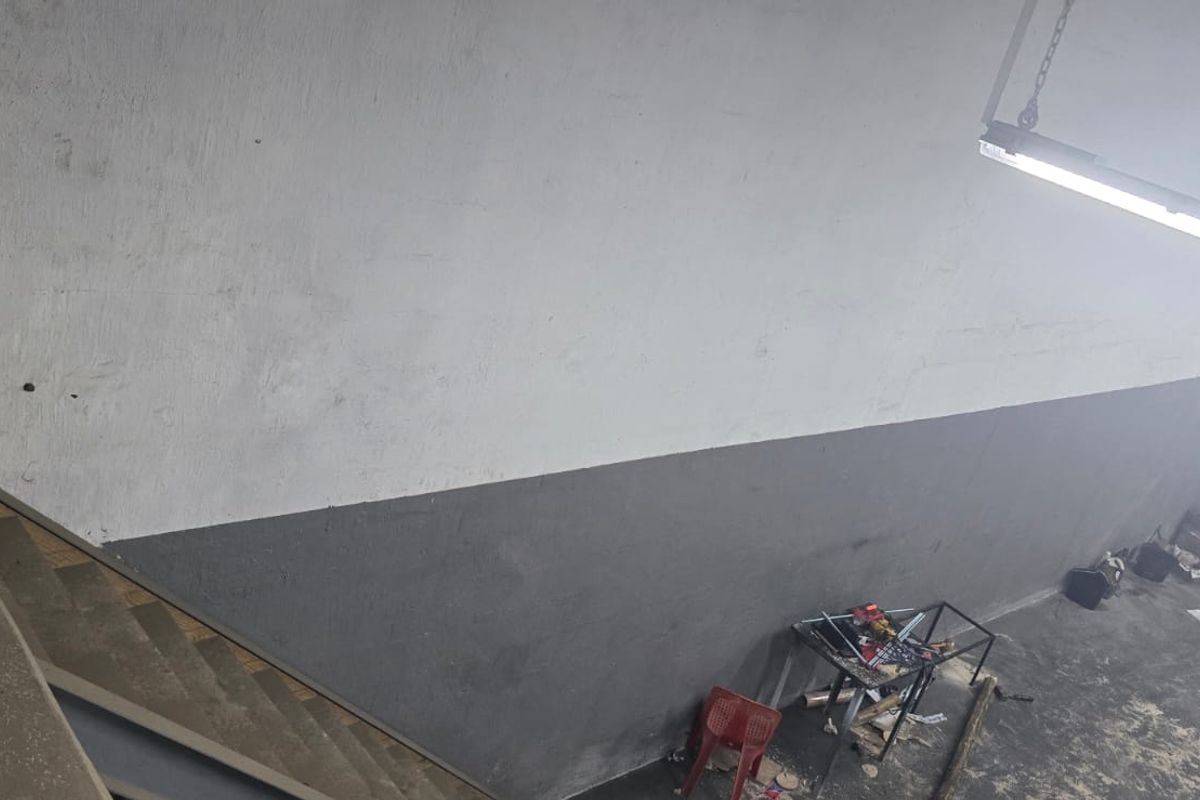 Industrial utility space featuring concrete stairs and high-mounted fluorescent lighting, suitable for storage or workshop use.