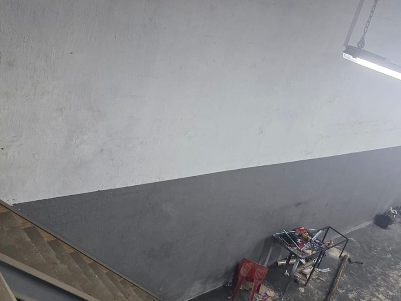 Industrial utility space featuring concrete stairs and high-mounted fluorescent lighting, suitable for storage or workshop use.