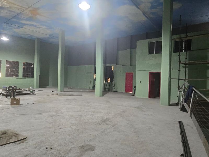Large open-plan industrial utility space featuring concrete flooring, structural columns, and high ceilings, currently undergoing renovation and maintenance.
