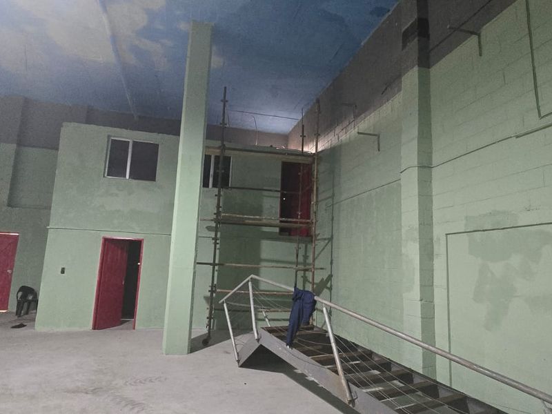 Large industrial utility space featuring concrete block walls, a metal staircase, and high ceilings, currently in an unfinished state suitable for various commercial uses.