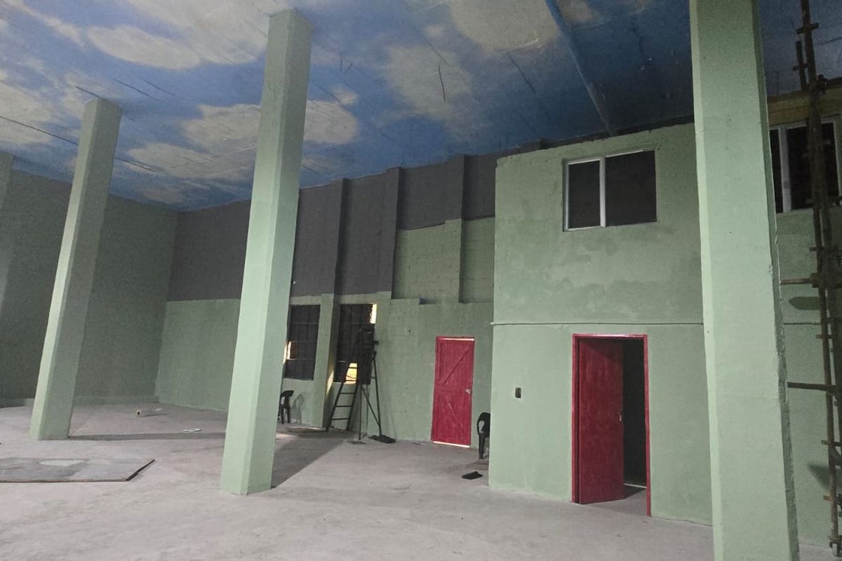 Spacious industrial open-plan area featuring high ceilings, concrete columns, and large windows, currently undergoing renovation and interior finishing.