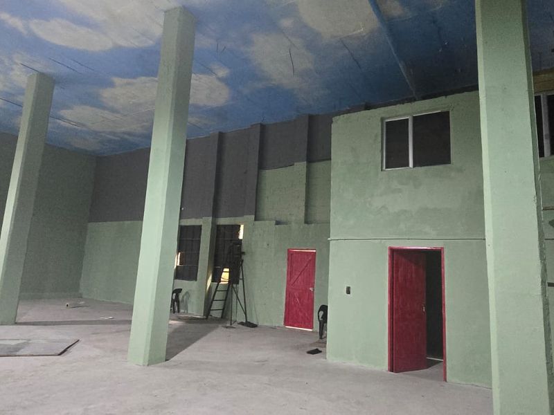 Spacious industrial open-plan area featuring high ceilings, concrete columns, and large windows, currently undergoing renovation and interior finishing.