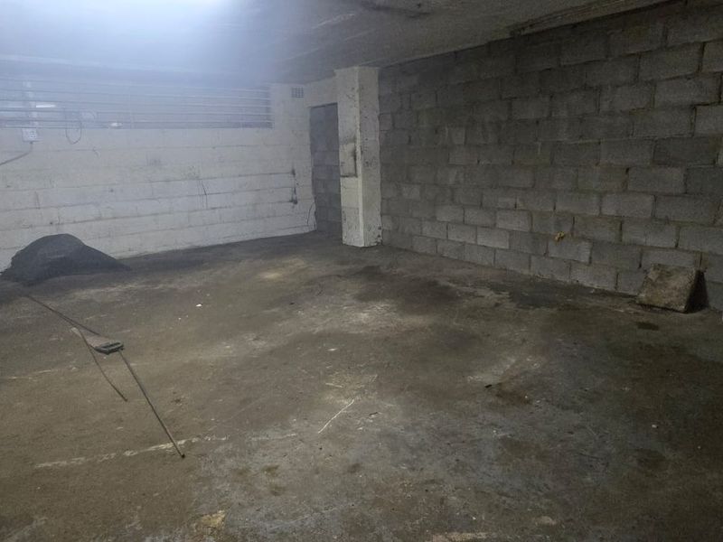An empty industrial garage space featuring exposed concrete block walls, concrete flooring, and functional louvre windows.