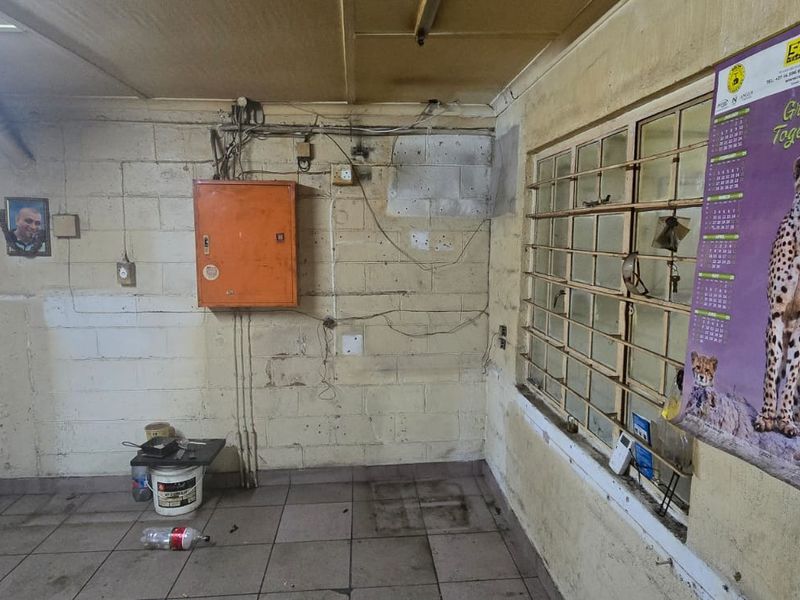 A functional utility space featuring tiled flooring, security bars on the window, and an exposed electrical distribution board, requiring maintenance and cosmetic updates.