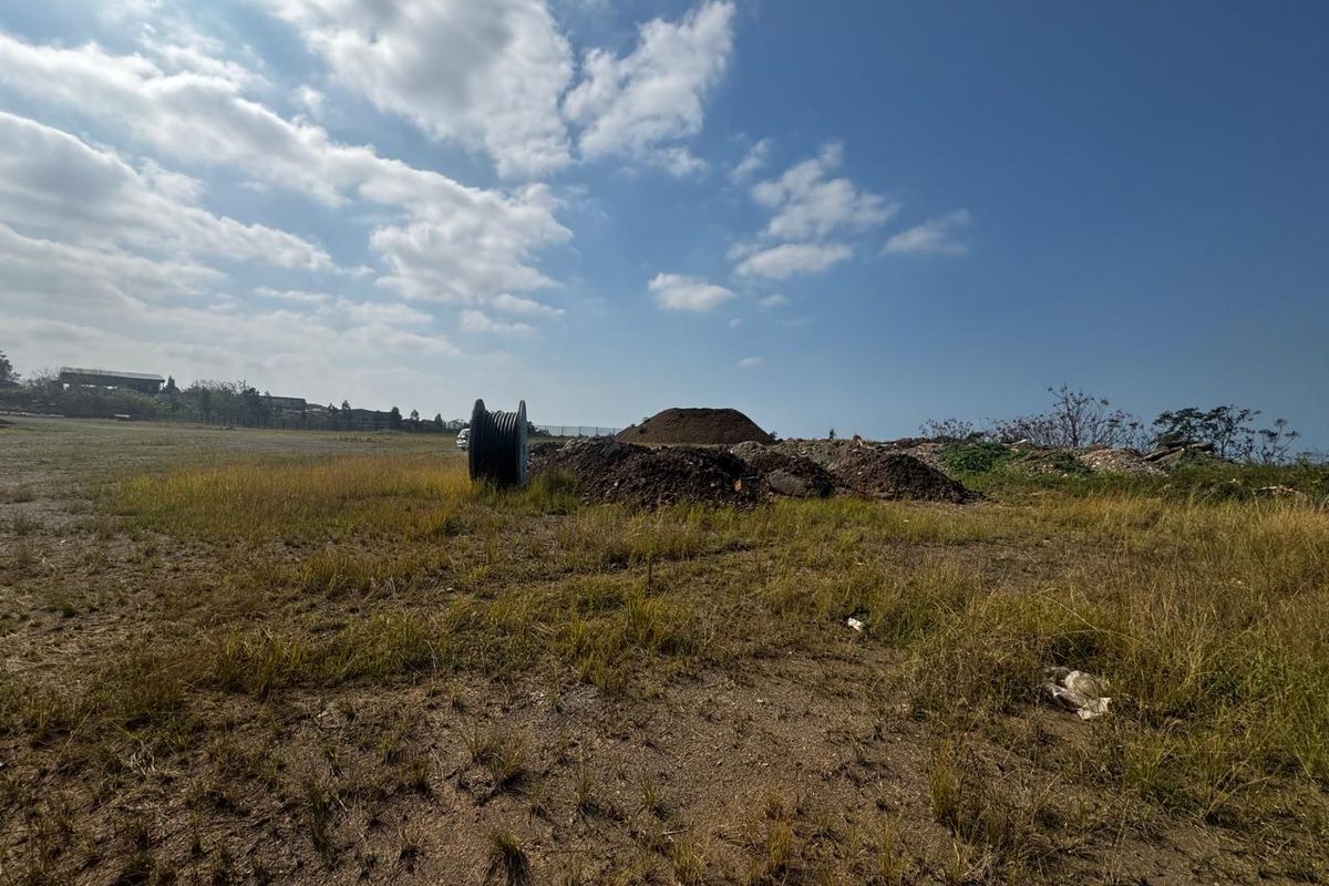 A view of a vacant commercial land plot featuring uneven terrain and piles of earth, suitable for future development.