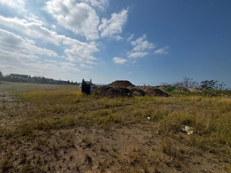 A view of a vacant commercial land plot featuring uneven terrain and piles of earth, suitable for future development.