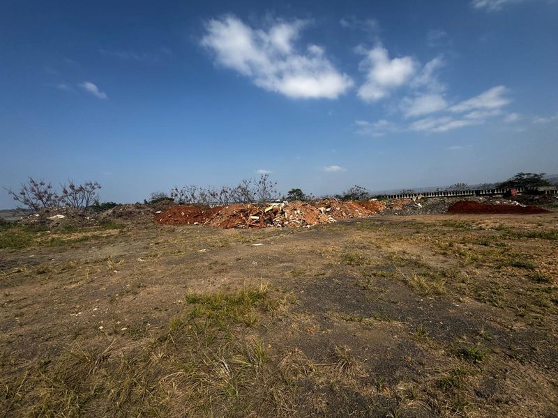 A view of the vacant commercial land featuring piles of debris and uneven terrain across the site.