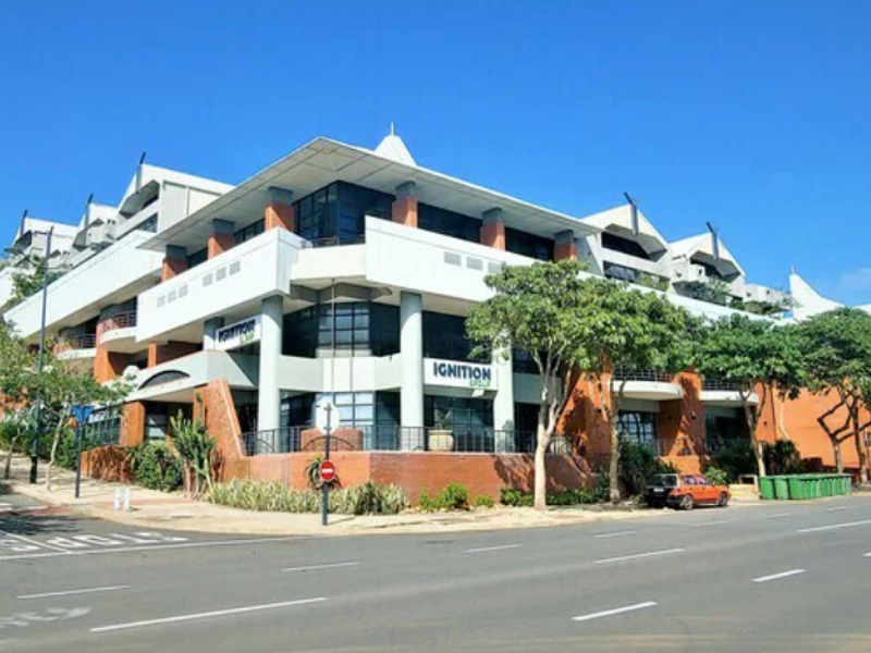 A modern multi-story office building featuring a prominent brick and glass facade with integrated balconies and professional architectural design.