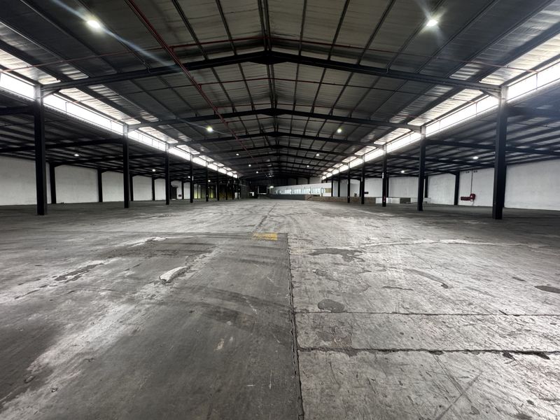 Expansive industrial warehouse space featuring a high-clearance steel portal frame, durable concrete flooring, fire sprinkler system, and ample natural light from clerestory windows.
