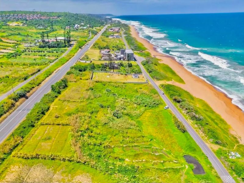 Aerial view of a vacant commercial land parcel situated along the coastline with direct road access and proximity to the beach.