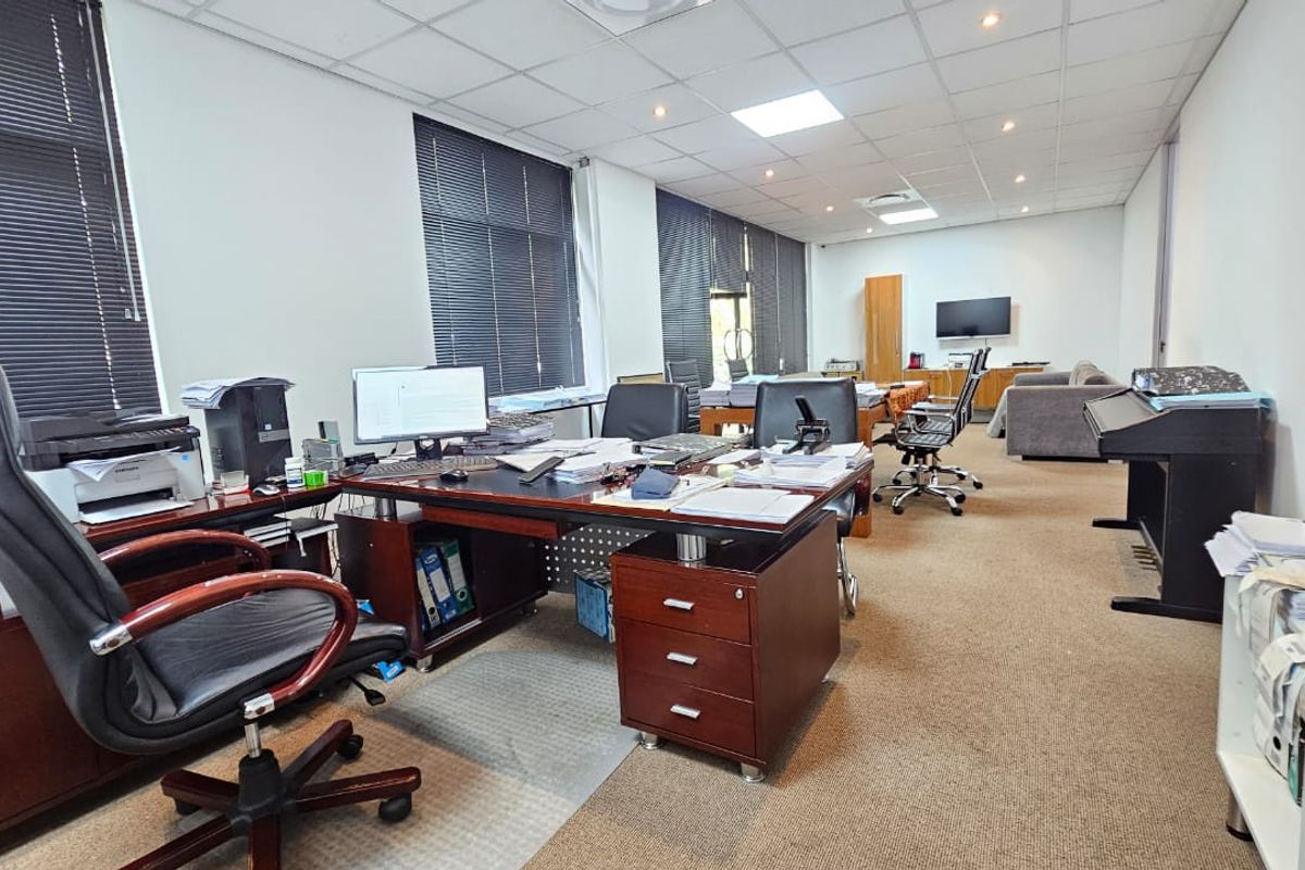 Spacious office area featuring suspended ceilings, recessed lighting, carpeted flooring, and large windows with venetian blinds.
