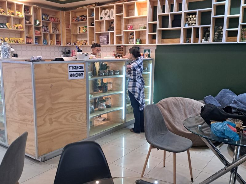 Office space featuring a custom wooden service counter, extensive built-in shelving units, recessed ceiling lighting, and polished tiled flooring.