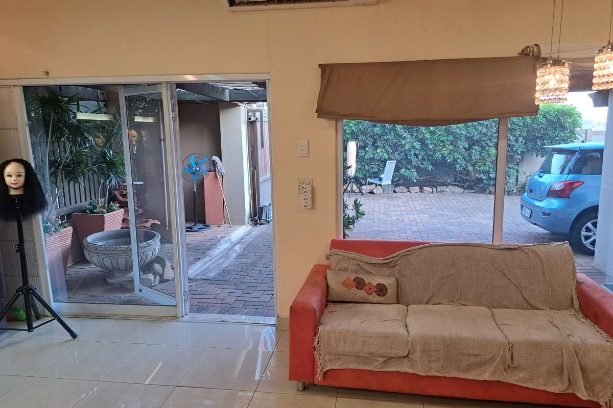 A bright living area featuring tiled floors, a split-system air conditioner, and large sliding glass doors providing direct access to an outdoor patio space.