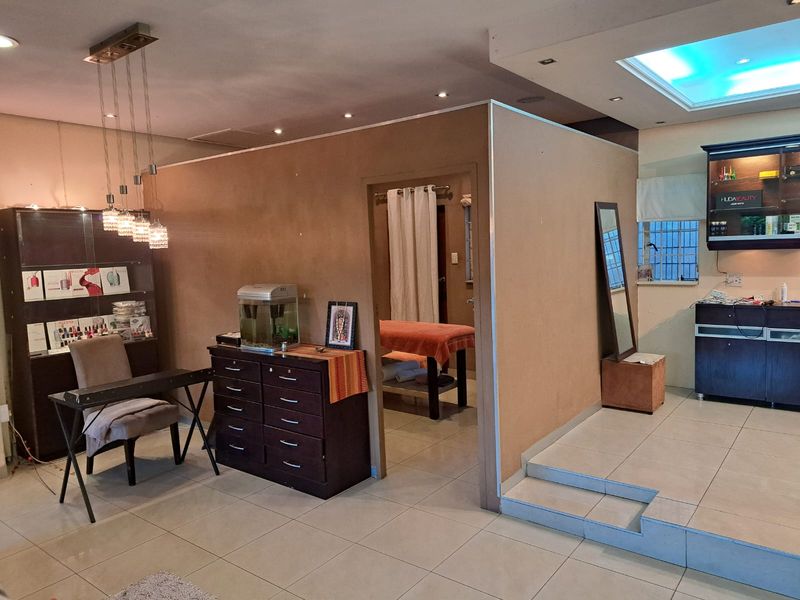 A commercial office space featuring tiled flooring, recessed lighting, and a partitioned room, suitable for a salon or professional service environment.