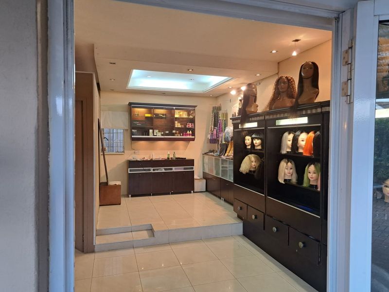 A commercial office or retail space featuring tiled flooring, recessed ceiling lighting, and extensive built-in display cabinetry with a raised platform section.