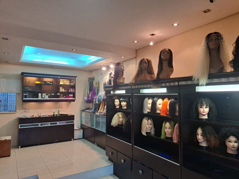 A commercial office space featuring built-in display cabinetry, recessed ceiling lighting, and tiled flooring, currently utilized for retail display.