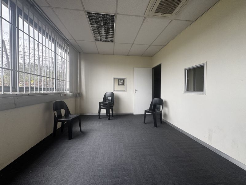 A functional office space featuring carpet tiles, a suspended ceiling with recessed lighting, ducted air conditioning, and security bars on the windows.