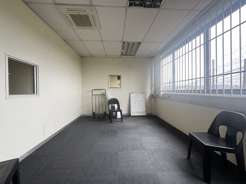 A functional office space featuring a suspended ceiling with recessed lighting, ducted air conditioning, and security bars on the windows.