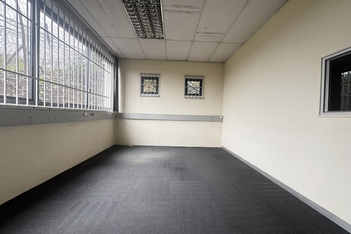 An empty office space featuring carpeted flooring, recessed ceiling lighting, and security bars on the windows.