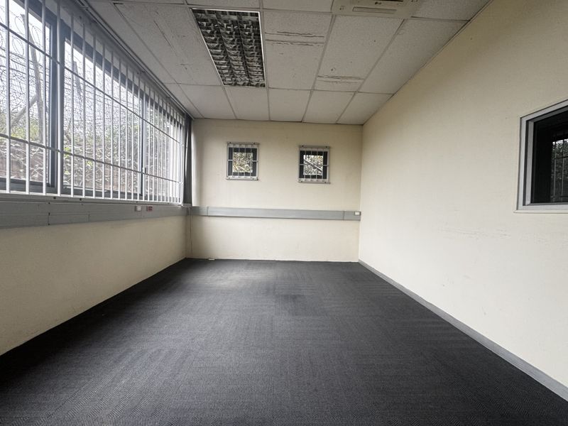 An empty office space featuring carpeted flooring, recessed ceiling lighting, and security bars on the windows.
