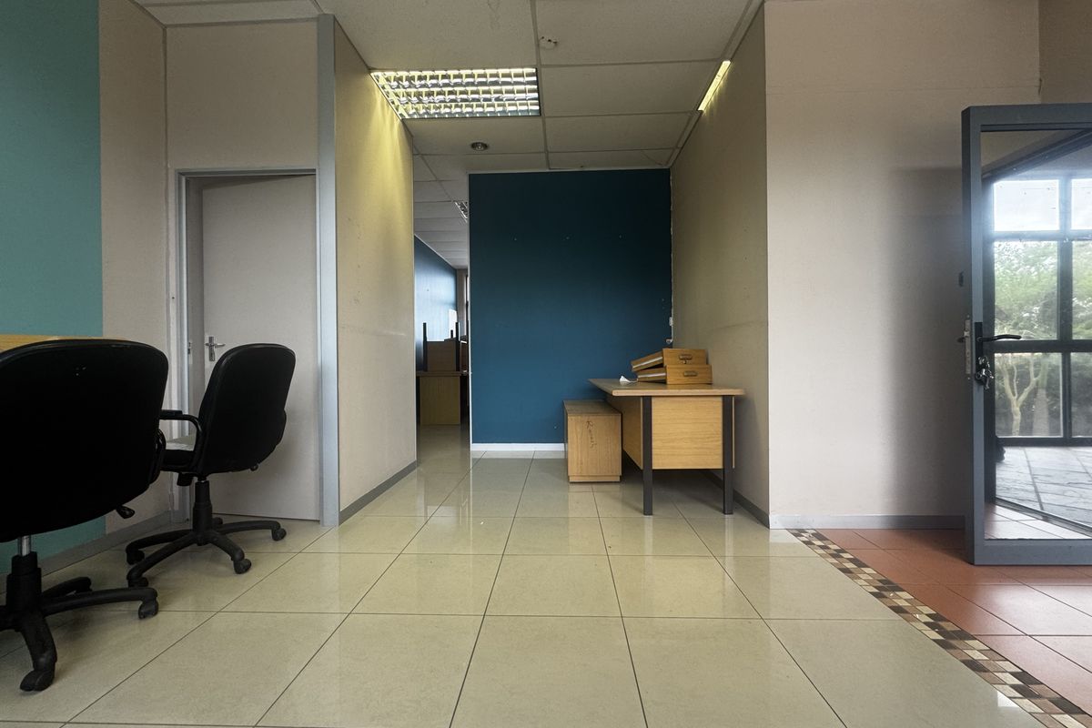 An office space featuring ceramic tiled flooring, suspended ceiling with recessed lighting, and partition walls, offering a functional layout for professional use.