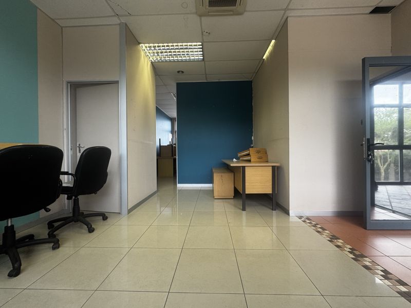 An office space featuring ceramic tiled flooring, suspended ceiling with recessed lighting, and partition walls, offering a functional layout for professional use.