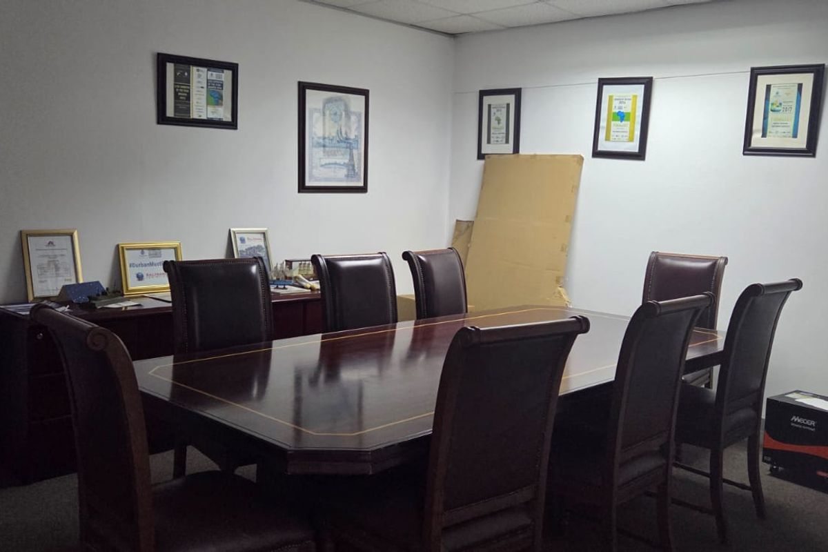 A functional office meeting room featuring a suspended ceiling and carpeted flooring, suitable for professional use.