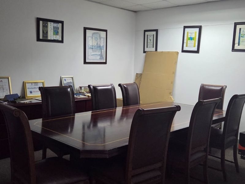 A functional office meeting room featuring a suspended ceiling and carpeted flooring, suitable for professional use.