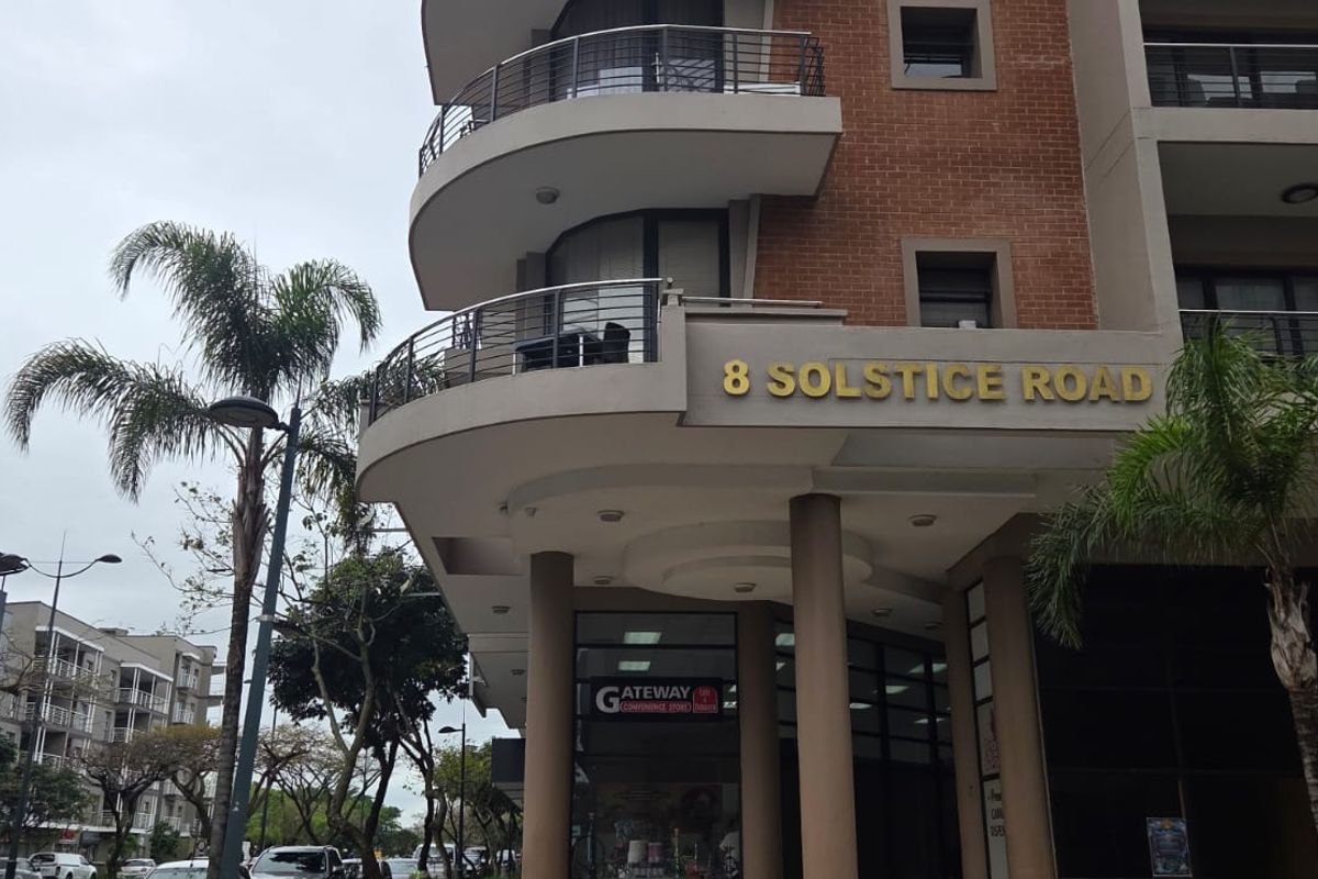 Exterior view of the office building facade at 8 Solstice Road, featuring curved balconies, brick detailing, and modern architectural design.