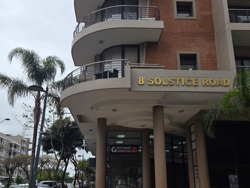 Exterior view of the office building facade at 8 Solstice Road, featuring curved balconies, brick detailing, and modern architectural design.