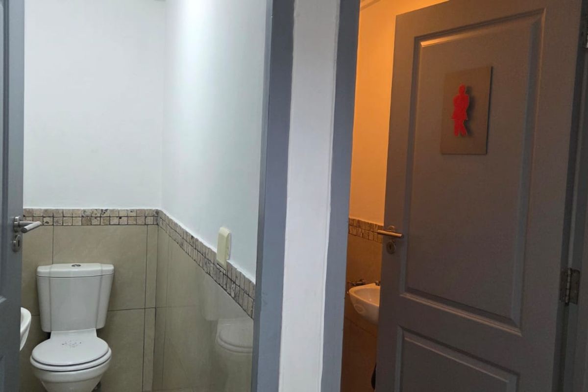 A functional office restroom facility featuring separate male and female designated entrances with tiled wall accents and standard sanitary fixtures.